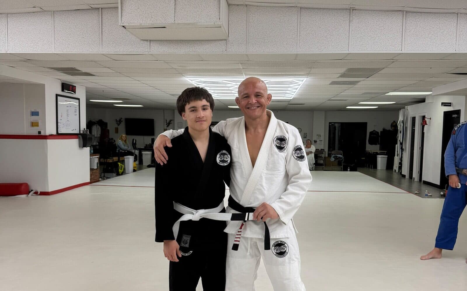 The open white training mats under hexagon lights at Carlson Gracie Hendersonville