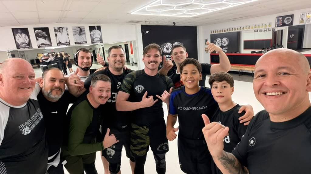 A team selfie after class, teenagers and adults smiling with Professor Paraíba