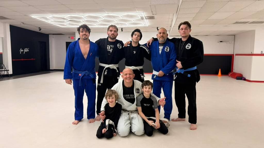 Kids and adults of the academy posing together on the mats
